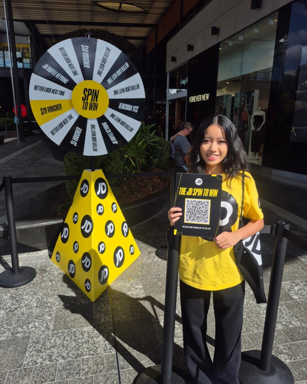 Brand ambassador demonstrating the Coin Drop game wheel outside the new JD Sports store