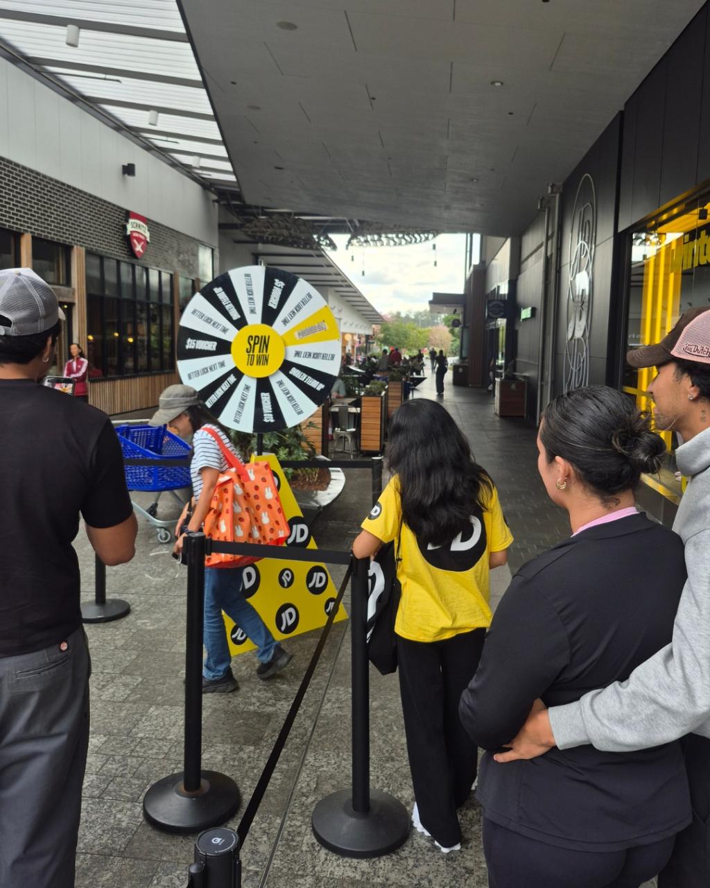 Shoppers and brand ambassadors gathered around the Coin Drop activation stand during the JD Sports store opening at Orion Springfield Central